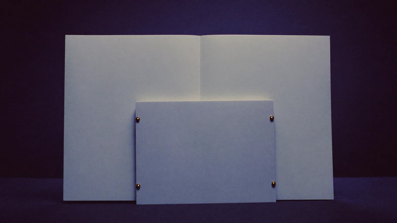 Two stacked blank title pages of different sizes standing upright, representing series title over episode title hierarchy, cinematic still