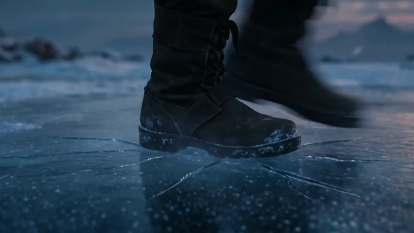 Gros plan d'une botte en cuir qui frappe la glace noire, des fissures se propagent